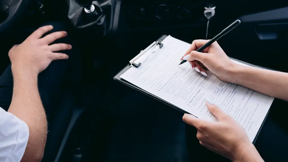 Un vendeur remet le certificat de situation administrative à un acheteur devant une voiture.